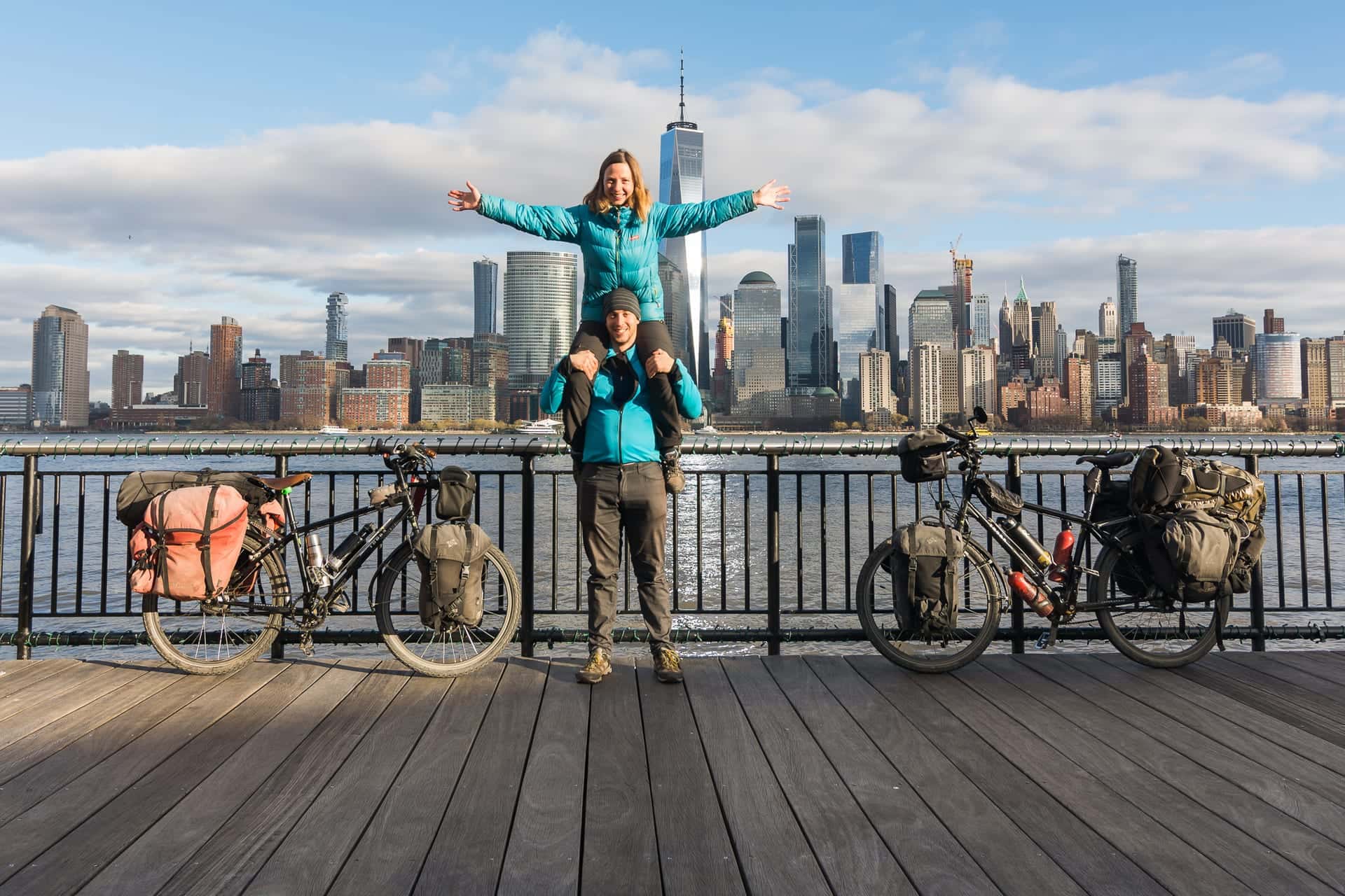 Pablo and Ilze with their loaded touring bikes in front of the New York skyline at the end of the round-the-world trip