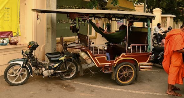 A tuk-tuk driver resting in a hammock